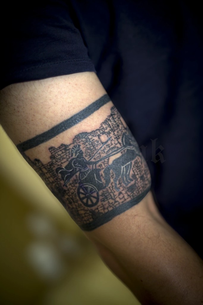 Tatouage en bandeau autour du bras, avec char antique et architecture romaine