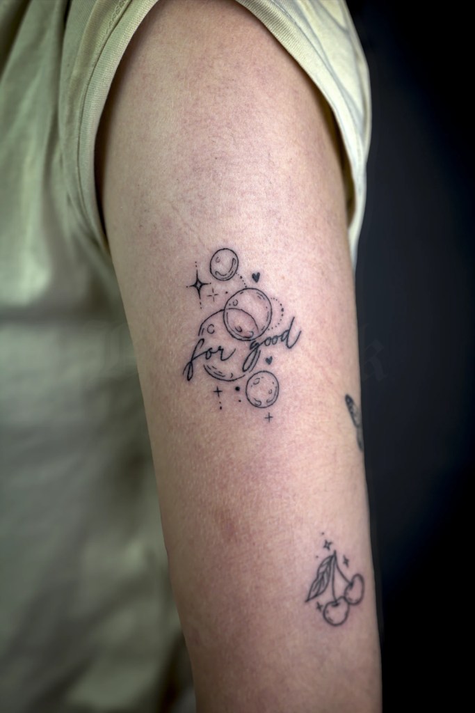 Petit tatouage de planètes, étoiles et lettrage sur le bras