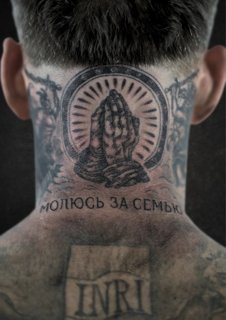 Mains jointes en prière dans une auréole, tatouées sur la nuque